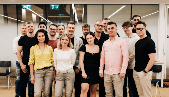 A group photo of sixteen people in a meeting room... after the meeting.