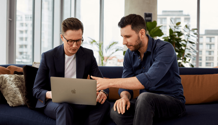 Two men consulting programming code.